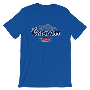 May include: A royal blue t-shirt with a distressed graphic of a raccoon and the text "Coonass Louisiana Since 1912".