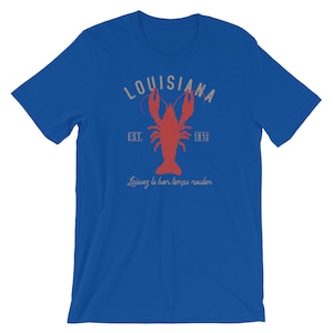 Op de afbeelding: Een koninklijk blauw t-shirt met een vintage-stijl grafische afbeelding van een rode kreeft, de tekst "Louisiana" in een witte boog en de tekst "Est. 1812" onder de kreeft. De tekst "Laissez le bon temps rouler" is onder de kreeft gedrukt.