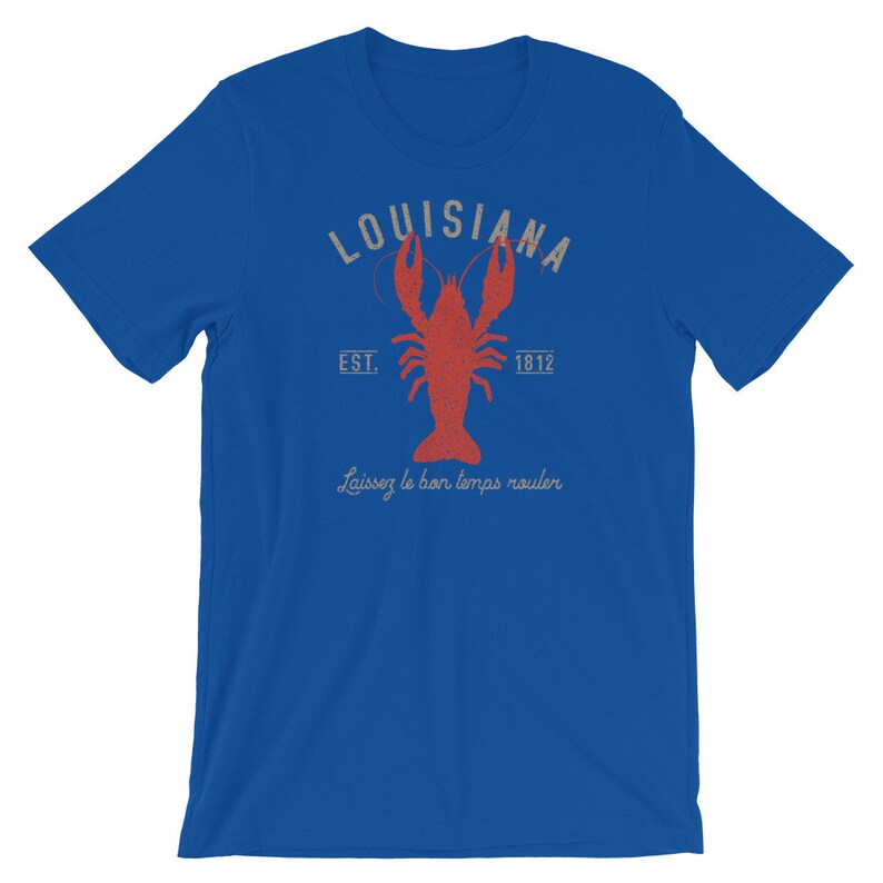 Op de afbeelding: Een koninklijk blauw t-shirt met een vintage-stijl grafische afbeelding van een rode kreeft, de tekst "Louisiana" in een witte boog en de tekst "Est. 1812" onder de kreeft. De tekst "Laissez le bon temps rouler" is onder de kreeft gedrukt.