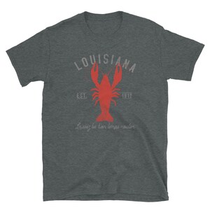 May include: A dark gray t-shirt with a red crawfish illustration and the text "Louisiana Est. 1812 Laissez les bon temps rouler".