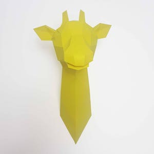 May include: A yellow papercraft giraffe head sculpture. The giraffe's head is made of folded paper and has a simple, geometric design.