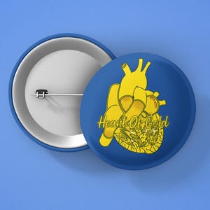 Könnte beinhalten: Ein blauer Knopf mit einem goldenen Herzen und dem Text "Heart of Gold" darauf.