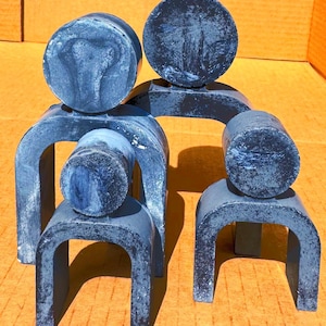 May include: A set of four blue and white ceramic sculptures in the shape of abstract figures. The sculptures are arranged in a family-like formation, with the largest sculpture in the back and the smallest sculpture in the front.