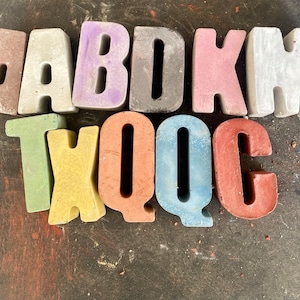 May include: A set of colorful alphabet blocks spelling out the word "ABQDC" in a mix of pastel colors, including pink, blue, green, yellow, and gray.