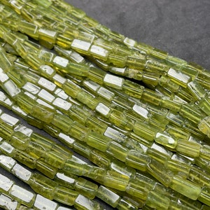 May include: A strand of green gemstone beads, each bead is a rectangular prism with a smooth, polished surface.