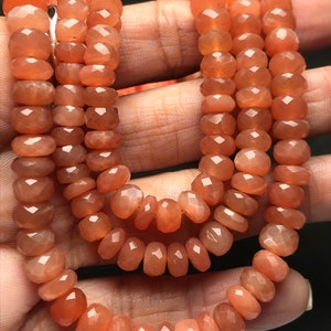 May include: A strand of orange sunstone beads with a faceted finish. The beads are strung on a cord and are approximately 6mm in diameter.