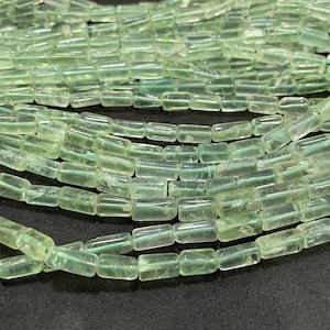 May include: A strand of light green, translucent, rectangular beads. The beads are made of natural stone and have a smooth, polished finish.
