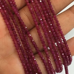 May include: Strands of small, faceted, deep red ruby beads. The beads are strung together, creating a flowing, textured appearance. The color is a rich, saturated red, with a slight sparkle from the facets. The beads are likely used for jewelry making.