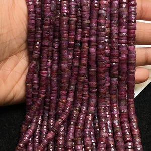 May include: Strands of faceted, deep red ruby beads. The beads are small, disc-shaped, and strung together, creating a rich, textured appearance. The color varies slightly, adding depth to the overall look. Ideal for jewelry making.