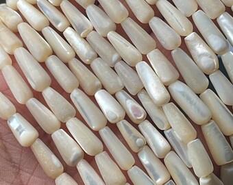 May include: A strand of white iridescent shell beads, each bead is a long, narrow, teardrop shape.
