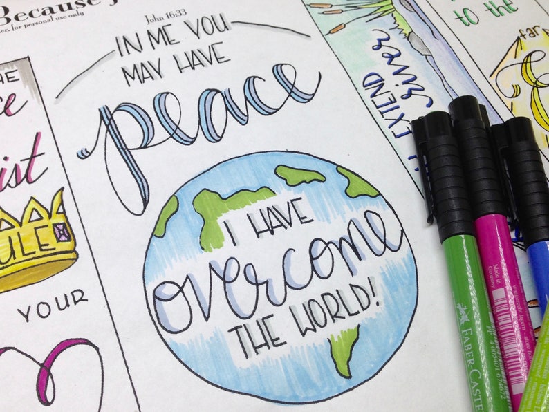 May include: A hand-drawn illustration of a globe with the words "I have overcome the world!" written in blue cursive. The globe is surrounded by a white background with the words "In me you may have peace" written in black cursive above the globe. The words "John 16:33" are written in black cursive above the words "In me you may have peace".