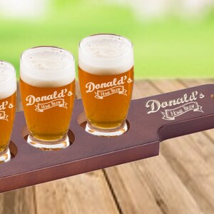 May include: A wooden beer flight tray with four clear glass beer tasting glasses. Each glass is engraved with the text "Donald's Home Brew".