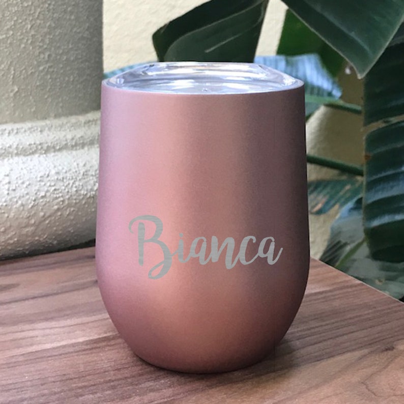May include: A rose gold stainless steel tumbler with a lid. The tumbler has the name "Bianca" engraved on the side.