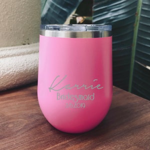 May include: Pink stainless steel tumbler with a white inscription that reads "Karrie Bridesmaid 10.2019"