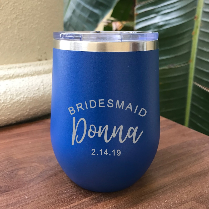 May include: Blue stainless steel tumbler with a white inscription that reads "BRIDESMAID Donna 2.14.19"
