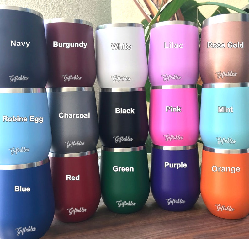 May include: A collection of 18 wine tumblers in various colors, including navy, burgundy, white, lilac, rose gold, robin's egg, charcoal, black, pink, mint, blue, red, green, purple, and orange. The tumblers are arranged in three rows of six, with the colors alternating in each row. The tumblers are all made of stainless steel and have a double-walled construction to keep drinks cold or hot for hours.