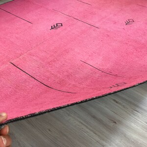 K&ouml;nnte beinhalten: Eine rosa Yogamatte mit schwarzen Linien und Pfeilen, die auf die Oberfl&auml;che gedruckt sind. Die Matte hat einen schwarzen Rand.