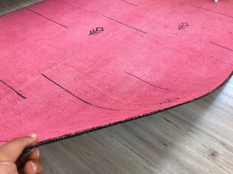 K&ouml;nnte beinhalten: Eine rosa Yogamatte mit schwarzen Linien und Pfeilen, die auf die Oberfl&auml;che gedruckt sind. Die Matte hat einen schwarzen Rand.