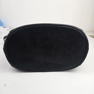 Pu&ograve; includere: Una borsa in pelle nera con base ovale. La borsa ha una consistenza liscia e un bordo superiore arrotondato. La borsa &egrave; progettata con uno stile semplice e classico.