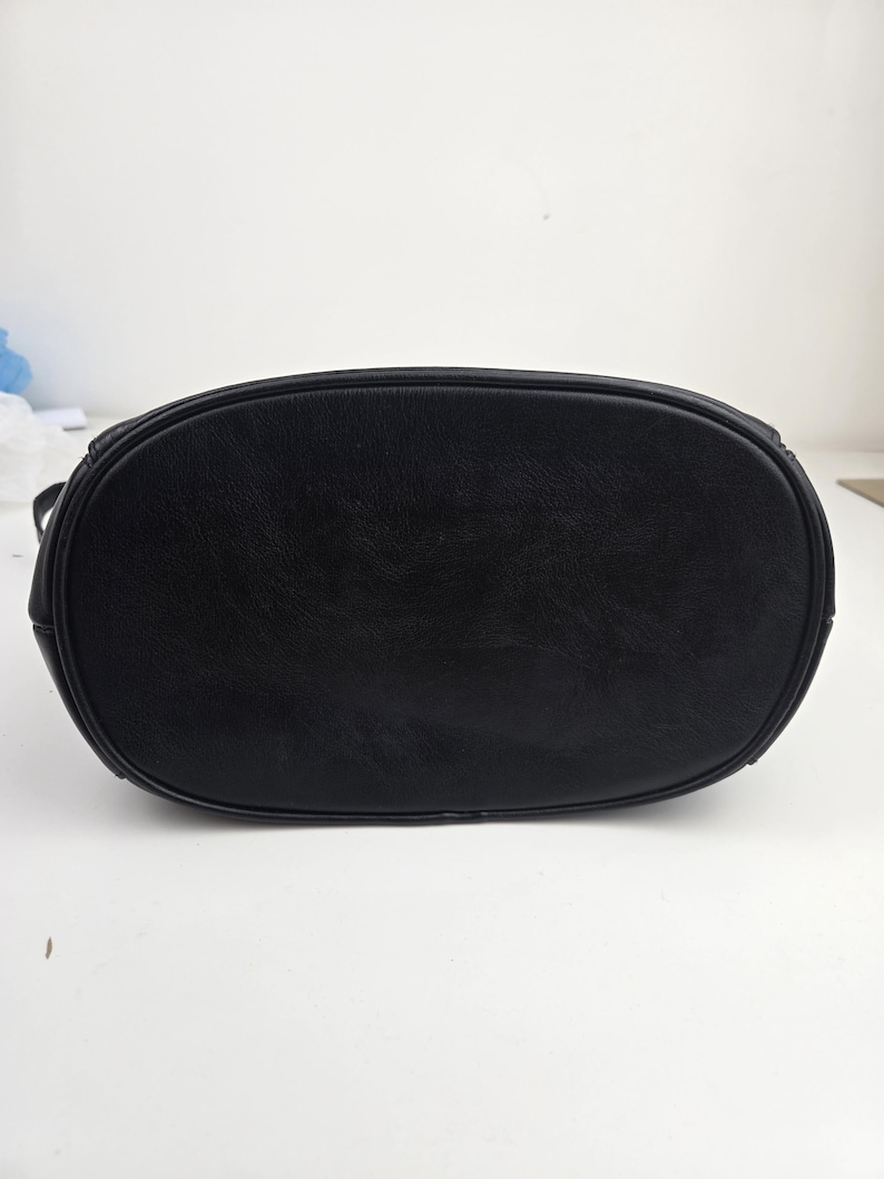 Pu&ograve; includere: Una borsa in pelle nera con base ovale. La borsa ha una consistenza liscia e un bordo superiore arrotondato. La borsa &egrave; progettata con uno stile semplice e classico.