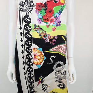 Puede incluir: Un vestido sin mangas con base color crema, negro y amarillo con un estampado gr&aacute;fico vibrante. El dise&ntilde;o incluye una guitarra roja, rosas coloridas, un zapato de tac&oacute;n, notas musicales, una flor de loto y el texto "VERSACE" en letras estilizadas.