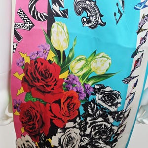 Puede incluir: Un vestido sin mangas con un estampado gr&aacute;fico vibrante en bloques de color rosa brillante y turquesa. El dise&ntilde;o incluye rosas rojas grandes, tulipanes blancos, flores moradas e ilustraciones de rosas en blanco y negro con texto.