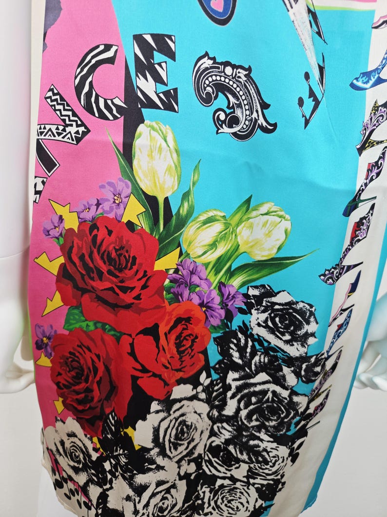 Puede incluir: Un vestido sin mangas con un estampado gr&aacute;fico vibrante en bloques de color rosa brillante y turquesa. El dise&ntilde;o incluye rosas rojas grandes, tulipanes blancos, flores moradas e ilustraciones de rosas en blanco y negro con texto.