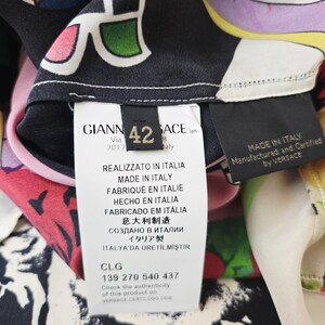 Puede incluir: Una prenda de seda multicolor con un estampado gr&aacute;fico llamativo de estrellas y formas abstractas. Incluye una etiqueta blanca con el texto GIANNI VERSACE, talla 42, MADE IN ITALY y el c&oacute;digo de autenticaci&oacute;n CLG 139 270 540 437.