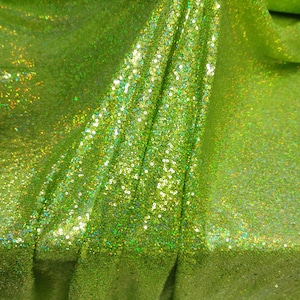 May include: Green iridescent fabric with sequins. The fabric is folded and shows the texture of the sequins.
