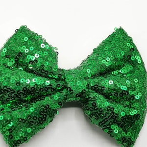 May include: A green sequin bow. The bow is made of small, round sequins that are sewn together to create a shiny, festive look.