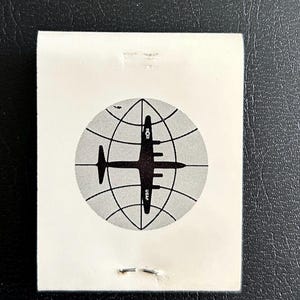 May include: A black and white illustration of a plane flying over a globe with the text "USAF" on the plane.