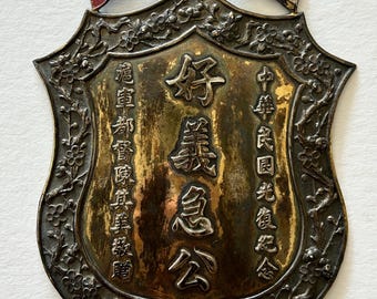 Rara placa comemorativa da Revolução Chinesa de 1911, concedida pelo Governador Militar Chen Qimei, em metal misto com borda em formato de flor de ameixa e esmalte.