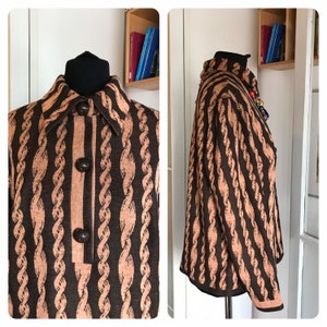 Pode incluir: Um suéter listrado marrom e bege com gola e fecho de botão. O suéter tem um padrão de corda.