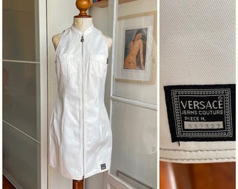 May include: White halter-neck dress with a zip-up front and two front pockets. The dress is displayed on a mannequin. A black label with the Versace Jeans Couture logo and the number 337327 is visible.