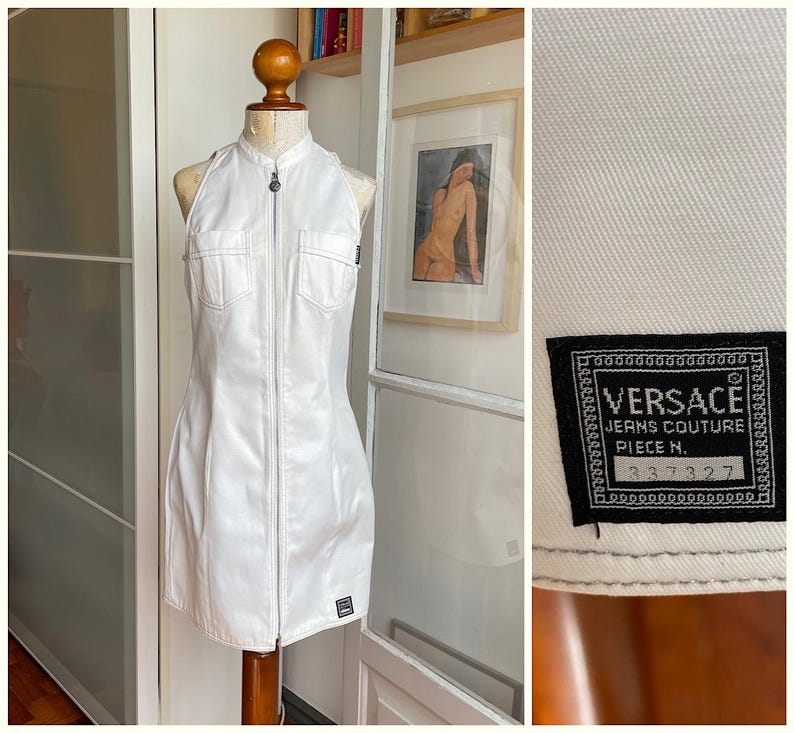 May include: White halter-neck dress with a zip-up front and two front pockets. The dress is displayed on a mannequin. A black label with the Versace Jeans Couture logo and the number 337327 is visible.