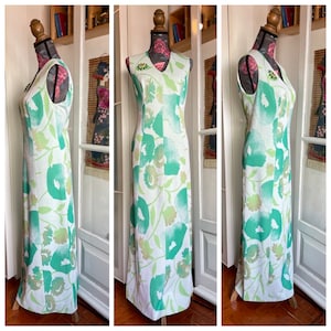 May include: A white maxi dress with a green floral print. The dress has a V-neckline and sleeveless design.