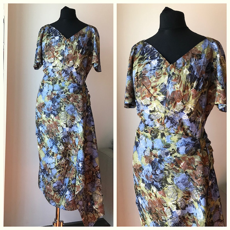 May include: A vintage wrap dress with a blue, brown, and green floral print. The dress has a V-neckline, short sleeves, and a fitted silhouette.