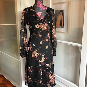 May include: A black midi dress with a floral print. The dress has long sleeves and a V-neckline.