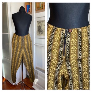 May include: A pair of yellow and black patterned pants with a zipper closure. The pants have a geometric design with a repeating pattern.
