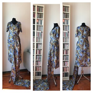 May include: A blue and brown floral print dress with a long train. The dress is on a mannequin and is displayed in a room with bookshelves.