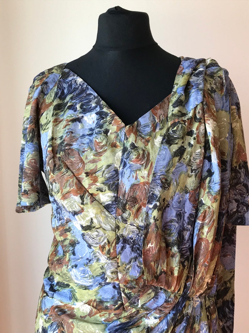 May include: A vintage dress with a V-neckline and short sleeves. The dress is made of a light-weight fabric with a blue, green, and brown abstract floral print.