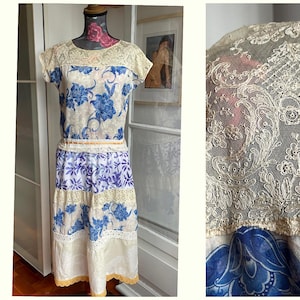 May include: A vintage dress with a blue and white floral design. The dress has a lace bodice and sleeves, and a tiered skirt. The dress is displayed on a mannequin.