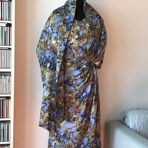 May include: A dress and matching scarf with a floral print in shades of blue, green, and brown. The dress has a fitted bodice and a flowing skirt.