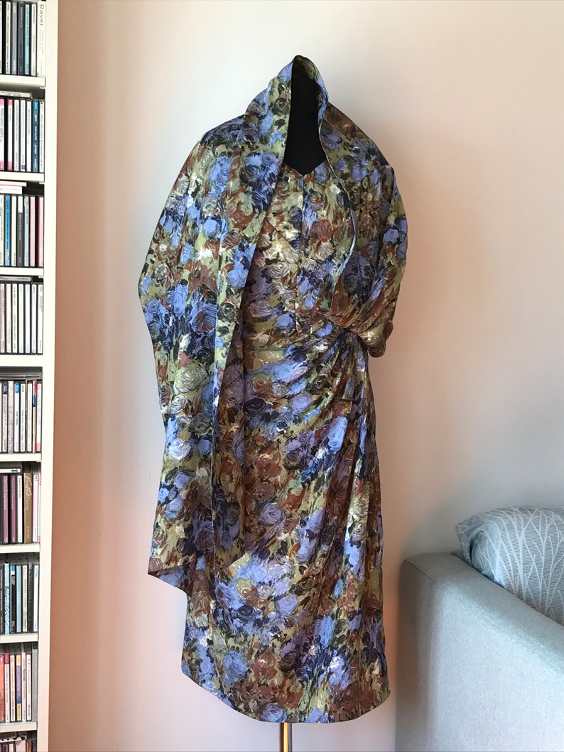 May include: A dress and matching scarf with a floral print in shades of blue, green, and brown. The dress has a fitted bodice and a flowing skirt.
