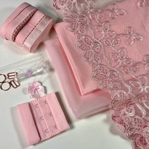 Könnte beinhalten: Ein rosa Lingerie-Bastelset mit Spitzenbesatz, Tüllstoff, elastischem Band, BH-Haken und einer Schleife.