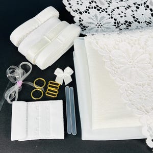 May include: A set of white bra strap making supplies including elastic, lace, mesh fabric, and hardware.