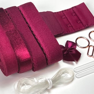 May include: A set of burgundy bra strap extenders with a hook and eye closure, a bow, two clear elastic bands, and two clear plastic pieces.
