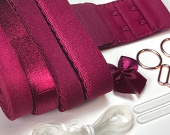 Könnte beinhalten: Ein Set mit burgunderfarbenen BH-Verlängerungen mit Haken- und Ösenverschluss, einer Schleife, zwei durchsichtigen Gummibändern und zwei durchsichtigen Plastikteilen.