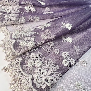 May include: Purple mesh fabric with white floral embroidery. The fabric has a delicate, lacy edge.