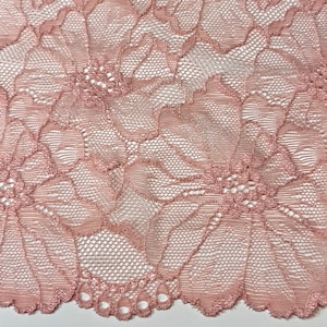 Peut inclure: Gros plan sur une dentelle rose délicate avec un motif floral. La dentelle a un bord festonné.